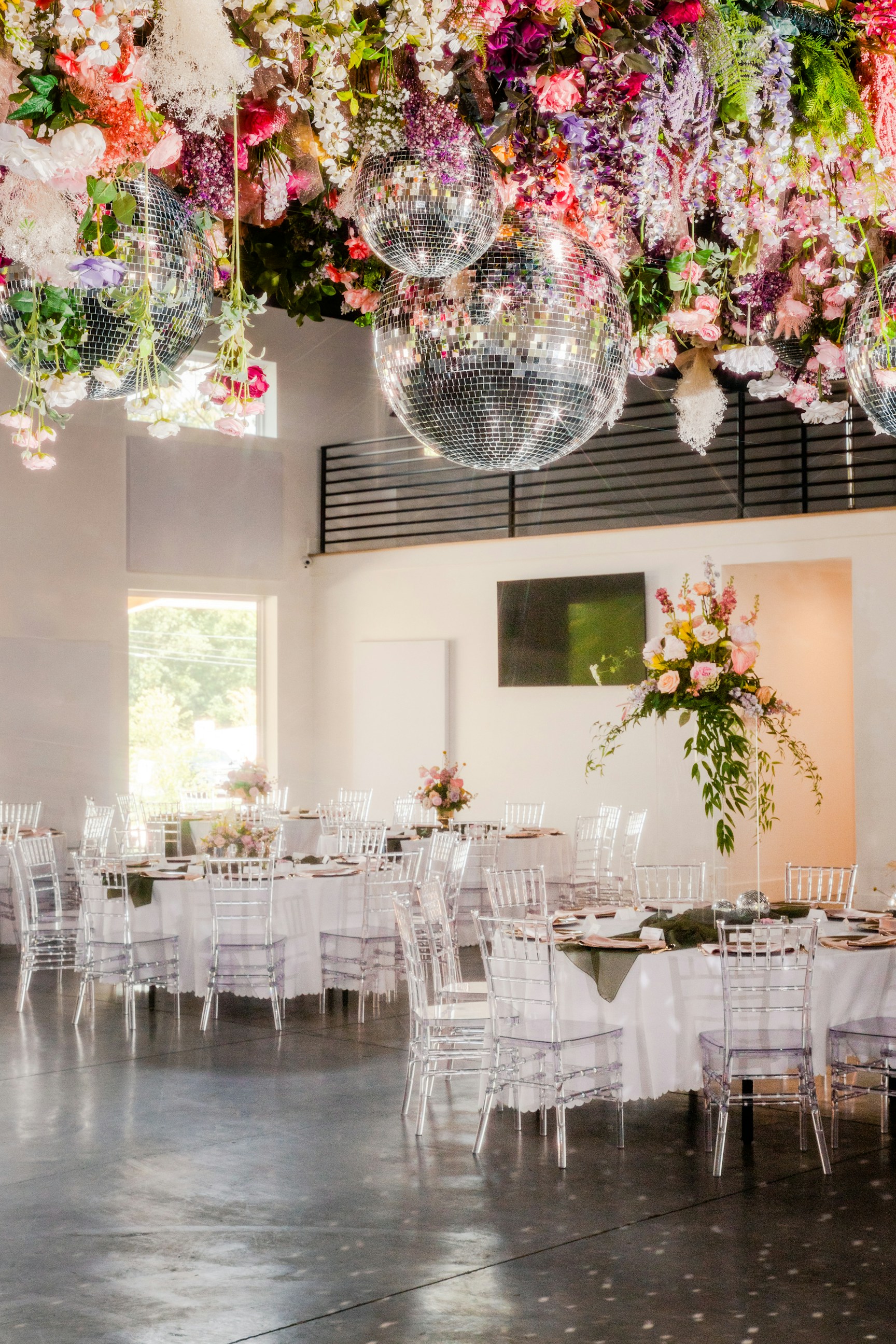 Bright reception room with clear chairs, florals and a disco ball