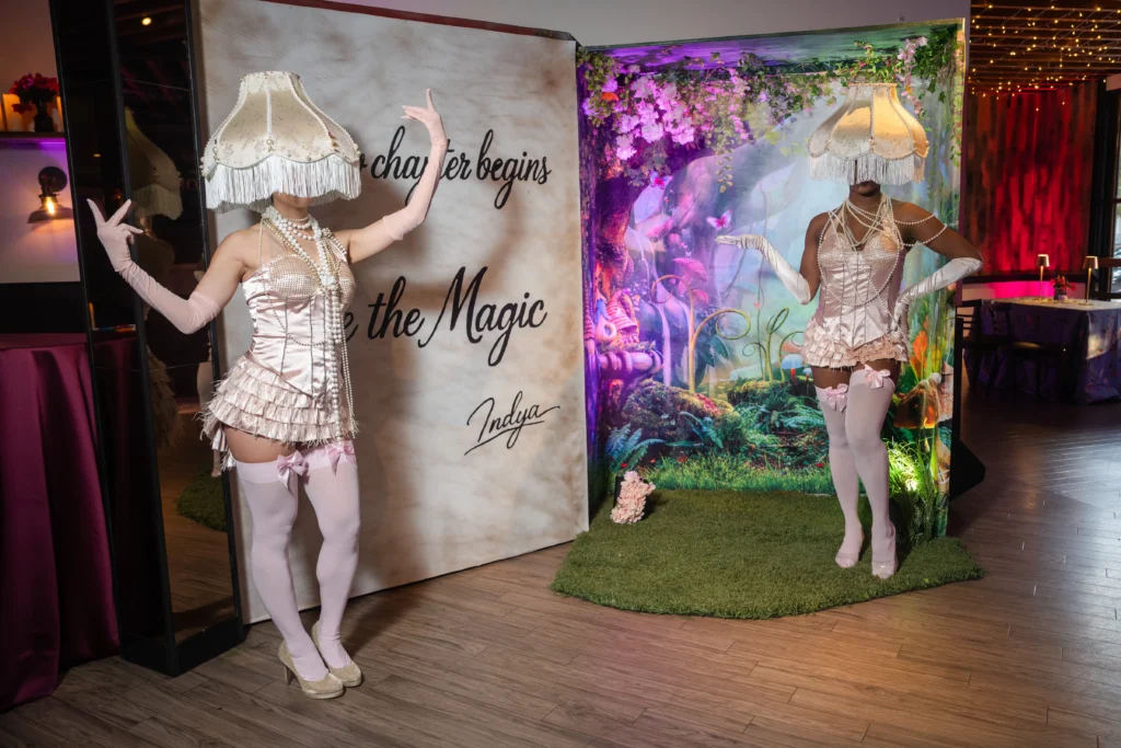 Costumed performers and a floral photo backdrop at a themed brand activation